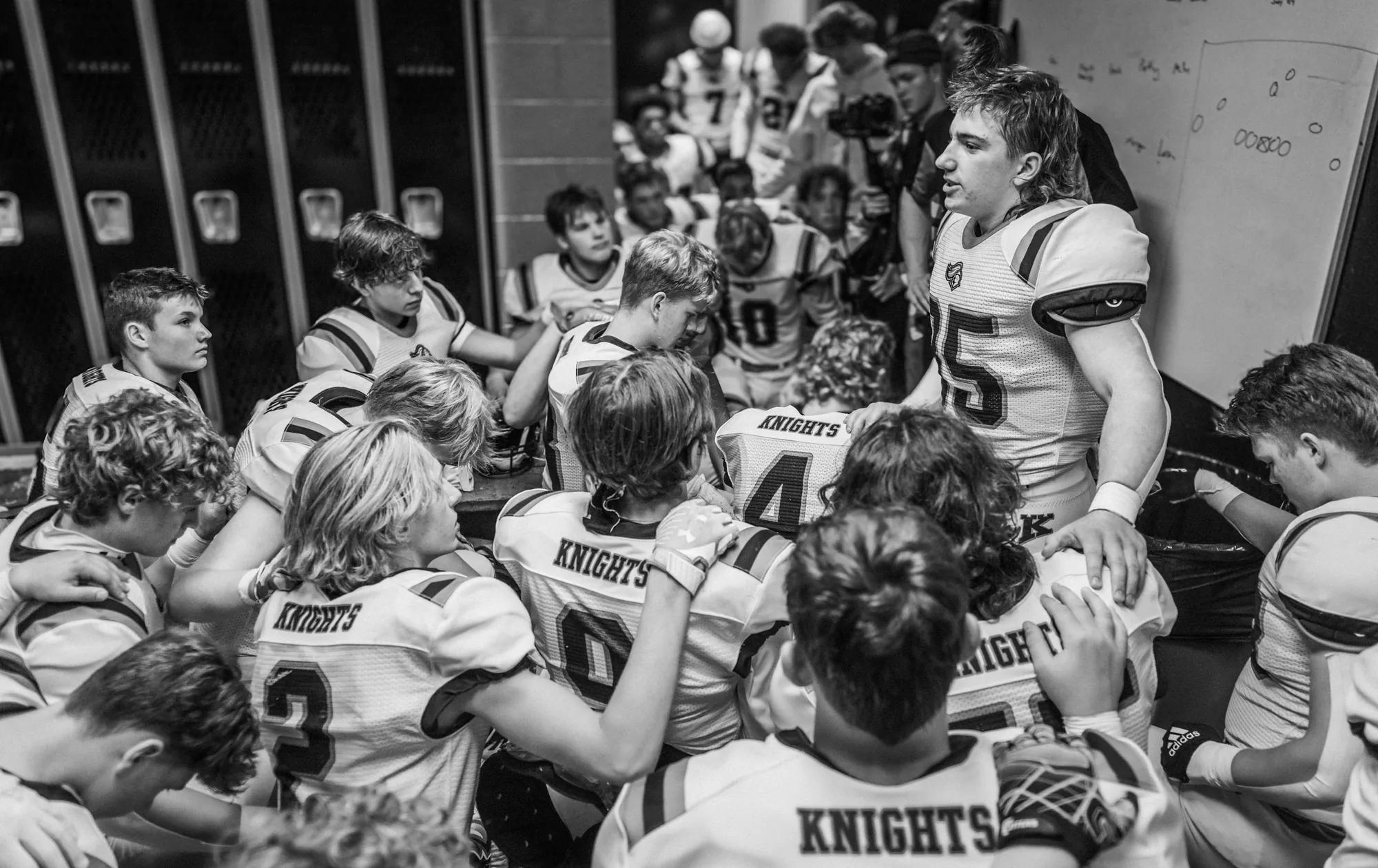 Joueurs de football américain réunis dans un vestiaire, en noir et blanc
