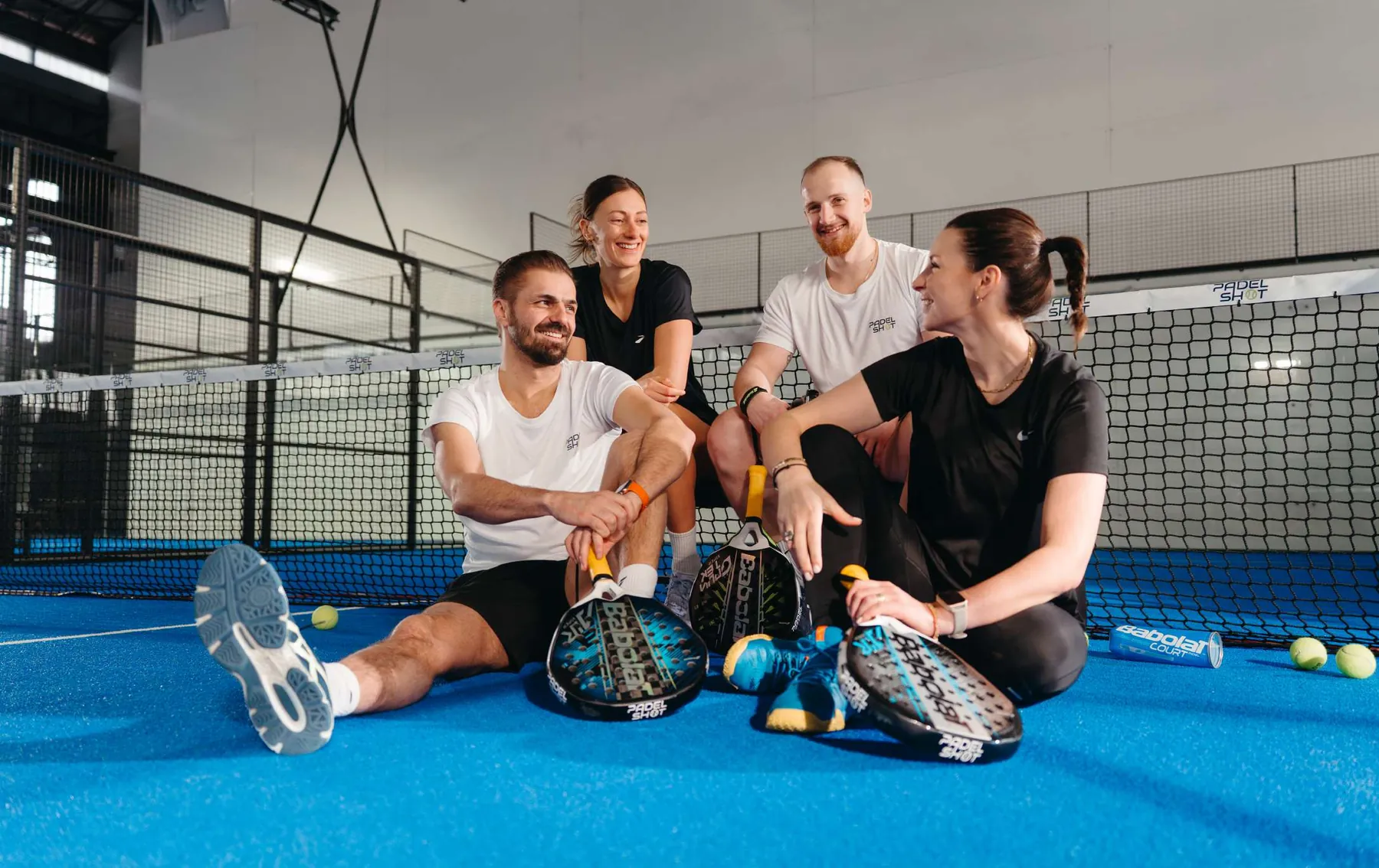 Quatre joueurs assis sur un terrain de padel Padel Shot, raquettes en main